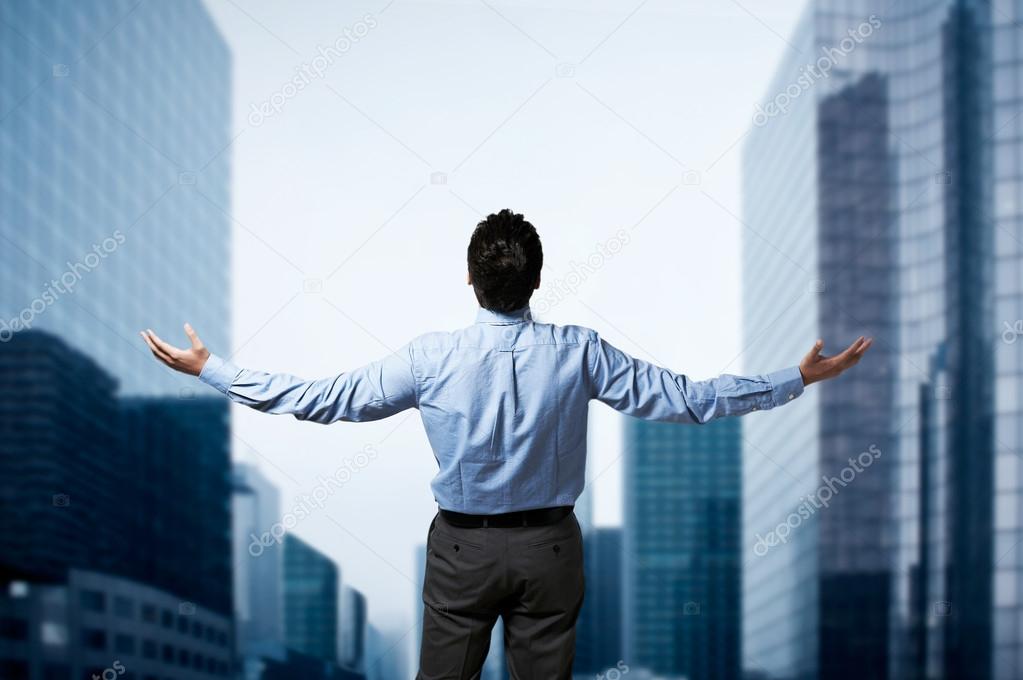 Young successful business man standing with arms wide open in fr