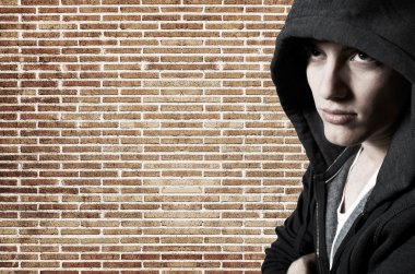 Young cool street style fashion male model posing at brick wall clipart