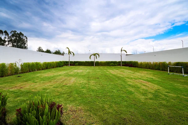 Großer Hof mit weißem Zaun, grünem Gras und blauem Himmel — Stockfoto