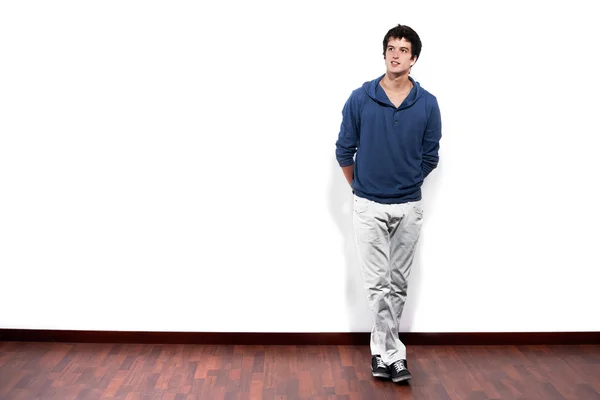 Young man relaxed against empty white wall with copy space — Stockfoto