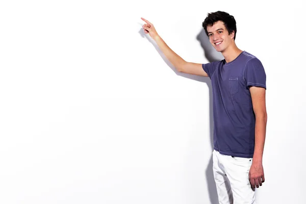 Joven relajado apuntando a la pared blanca — Foto de Stock