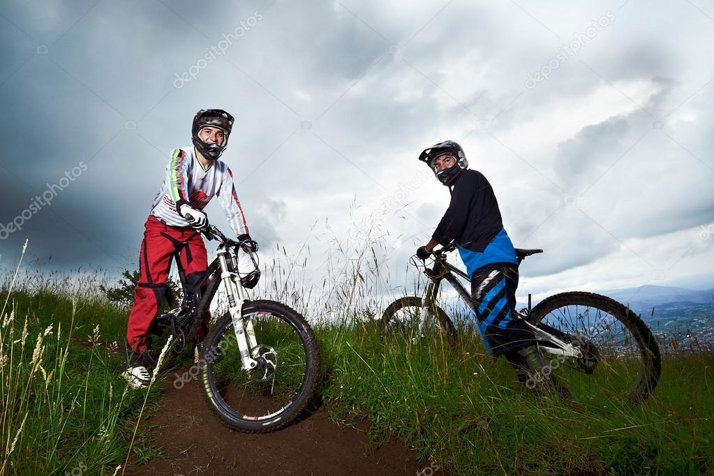 Two young man riding a mountain bike downhill style