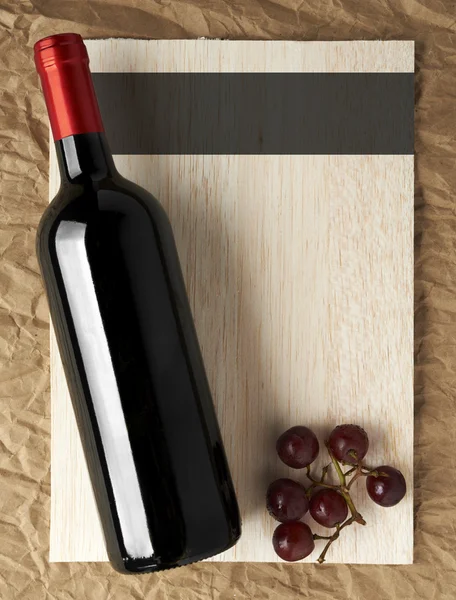 Wine List Design Series: Bottle of red wine and grapes over wood — Stock Photo, Image