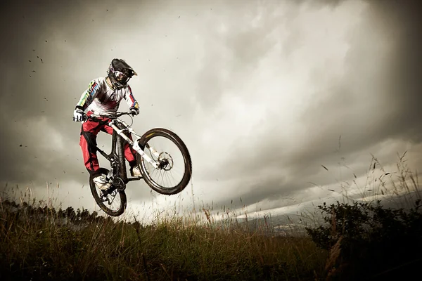 Giovane uomo in sella a una mountain bike in stile downhill — Foto Stock