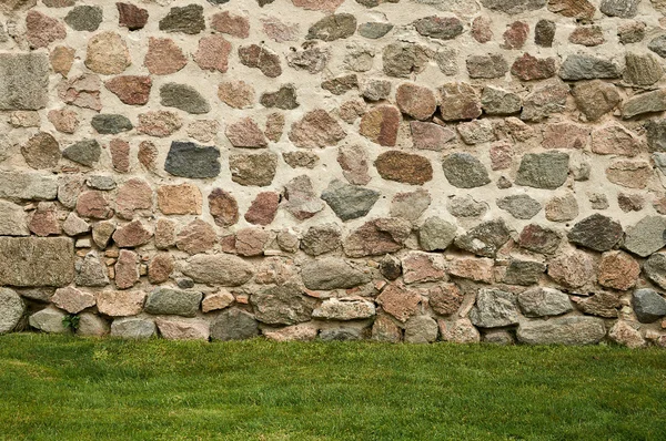 Achtergrond van stenen muur en groen gras — Stockfoto