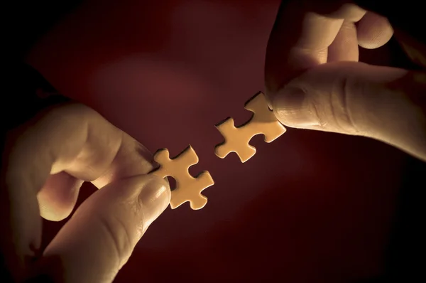 Hands trying to link two pieces of a puzzle — Stock Photo, Image