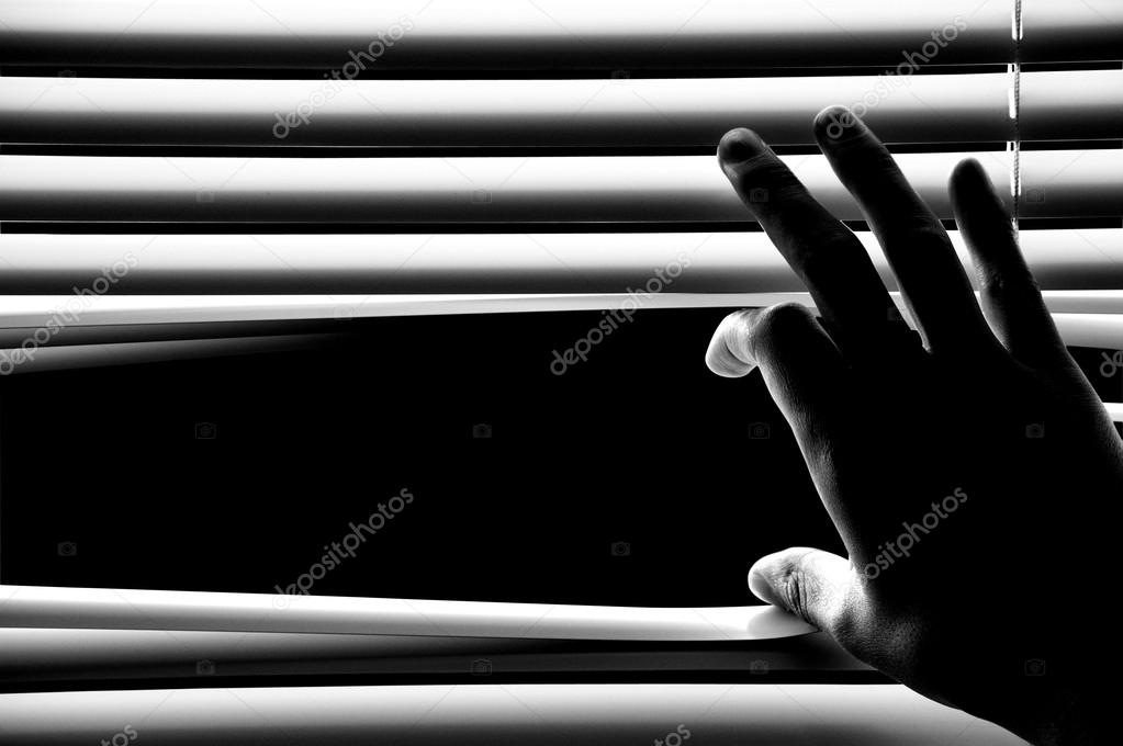 Man at office opening window blinds
