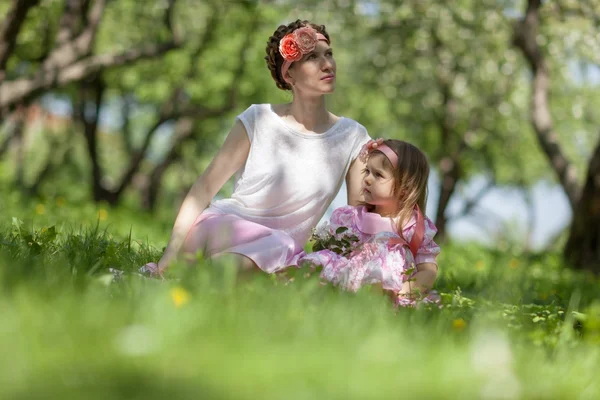 Flicka och kvinna i vårträdgård — Stockfoto