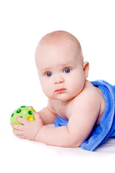 Baby i en blå handduk holding grön boll — Stockfoto