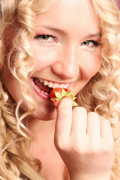 Blonde curly girl biting strawberry — Stock Photo, Image