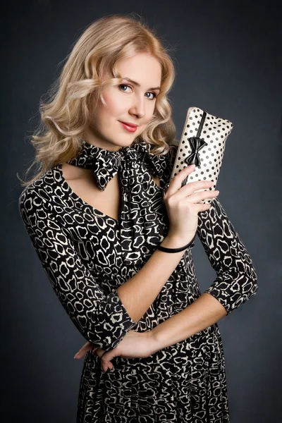 Schöne blonde Mädchen hält kleine schwarz-weiße Handtasche — Stockfoto