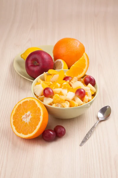 Two bowls with fruit salad on wooden table with half of orange — Stock Photo, Image