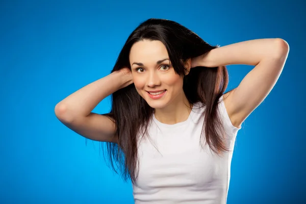 Mooie brunette meisje in wit t-shirt glimlachen over blauwe backg — Stockfoto