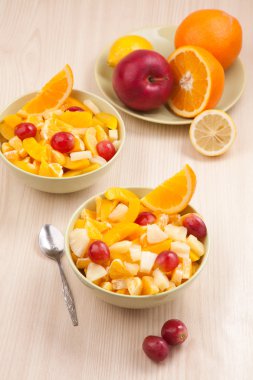 İki kase kaşık ile ahşap masa üzerinde meyve salatası ile