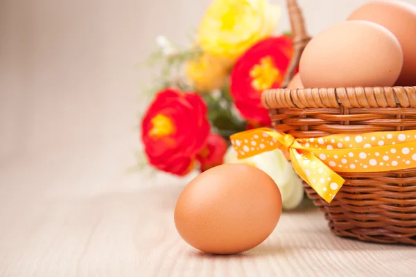 Un huevo cerca de una pequeña cesta con cintas y flores en madera ta —  Fotos de Stock