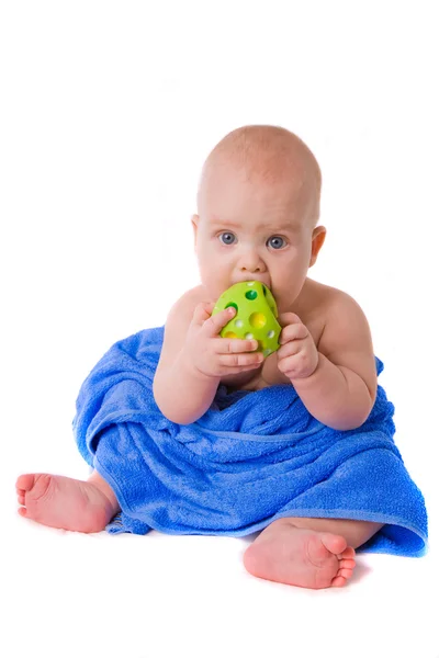 Little child in a blue towel biting green ball — Stock Photo, Image