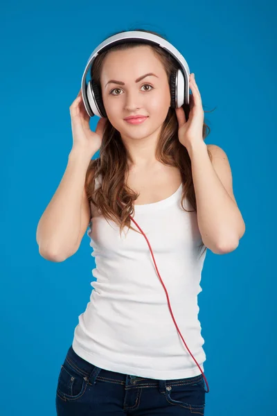 Bella ragazza sorridente ascoltando musica indossando cuffie bianche — Foto Stock