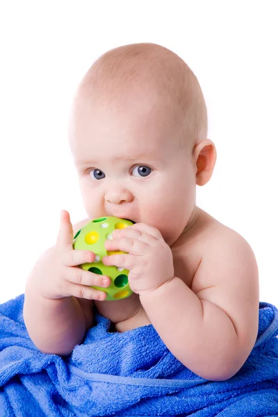 A beautiful baby wrapped in a blue towel biting green ball — Stock Photo, Image