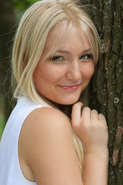Красивая блондинка стоит рядом с деревом — стоковое фото