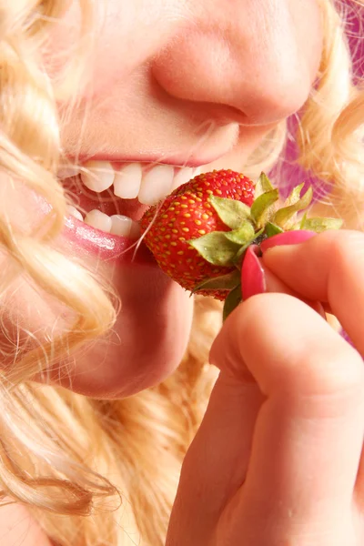 Blonde curly girl biting strawberry — Stock Photo, Image