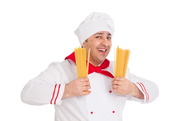 Sonriente cocinero vistiendo uniforme blanco sosteniendo macarrones crudos en t — Foto de Stock