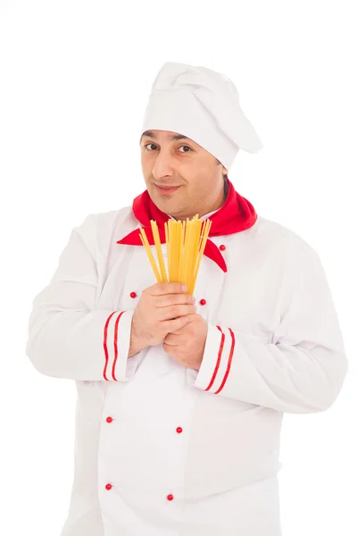 Smiling cook man wearing white uniform holding raw macaroni in t — Stock Photo, Image