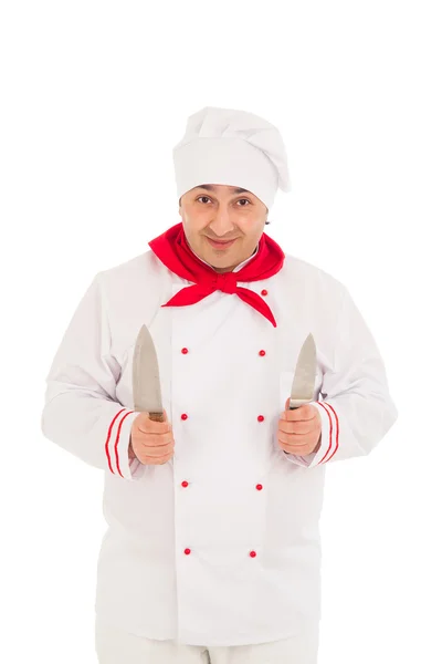 Szef uśmiechający się trzymając dwa noże, noszenie munduru czerwony i biały — Zdjęcie stockowe