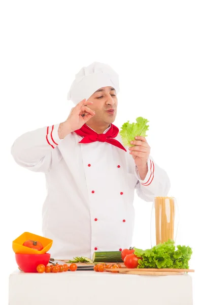 Happy chef holding leaf of salad and cooking with fresh vegetabl — Stock Photo, Image