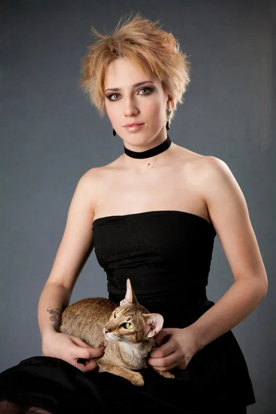 Hermosa joven rubia en vestido negro tenencia gato — Stockfoto