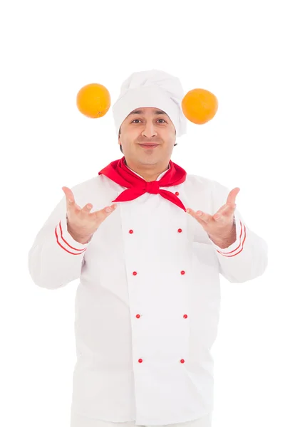 Feliz chef sosteniendo dos naranjas vistiendo uniforme rojo y blanco — Foto de Stock