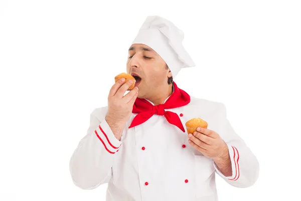 Chef degustação dois muffins vestindo uniforme vermelho e branco — Fotografia de Stock
