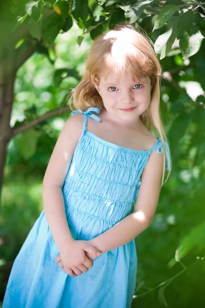 Klein meisje draagt blauwe jurk in het park — Stockfoto