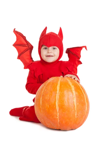 Niño pequeño en traje de diablo rojo sentado cerca de la calabaza grande —  Fotos de Stock