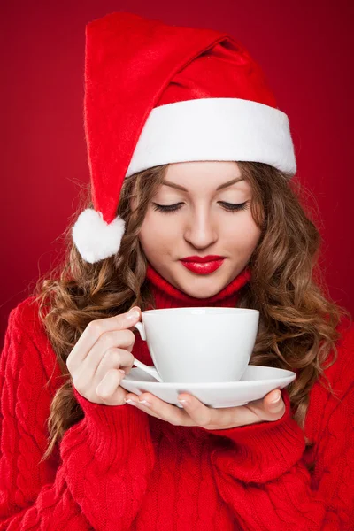 Brunette girl in Santa Clause hat holding white mug — Stock Photo, Image