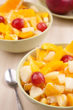 İki kase kaşık ile ahşap masa üzerinde meyve salatası ile