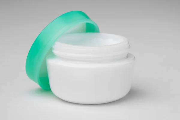 Envase cosmético de crema facial abierto con tapa verde —  Fotos de Stock