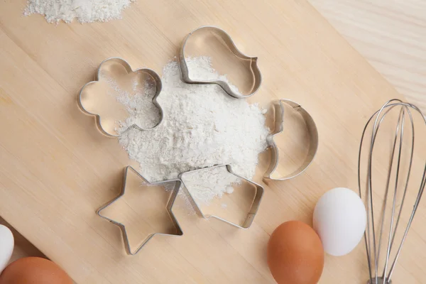 Raccolta di forme tagliabiscotti intorno alla farina su tavola di legno — Foto Stock