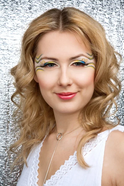 Mooie jonge vrouw portret met heldere gele en blauwe make-up en lange wimpers — Stockfoto