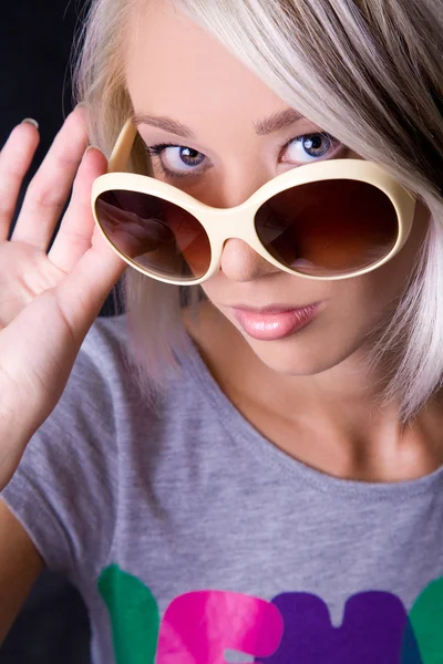 Ξανθιά νεαρή γυναίκα, κρατώντας τα γυαλιά ηλίου σε στούντιο金发碧眼的年轻女子，在播音室里捧着眼镜孙 — 图库照片