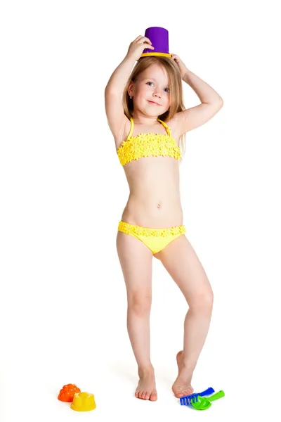Kleines blondes glückliches Mädchen im gelben Badeanzug mit lila Spielzeug Stockfoto