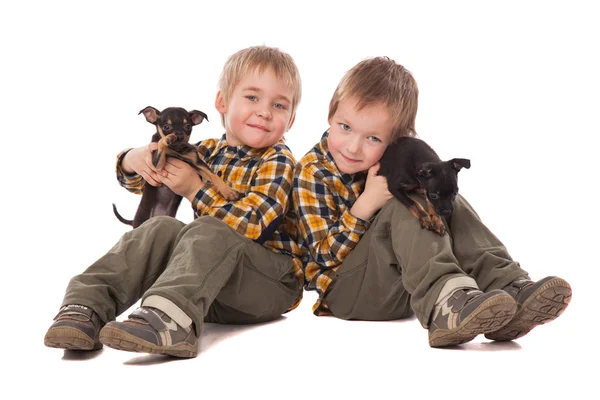 Sonrientes chicos sosteniendo cachorros yacen en el suelo —  Fotos de Stock