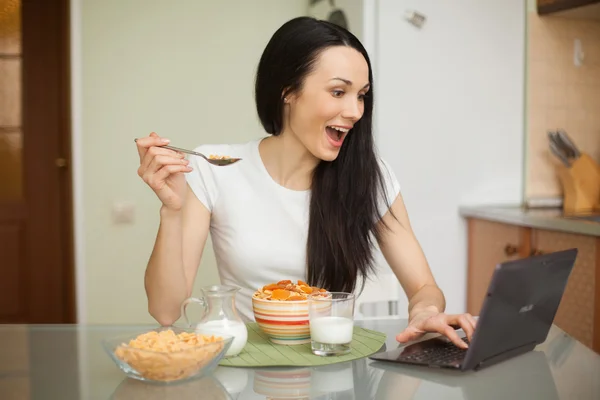 Dívka snídat a pomocí její laptop v kuchyni — Stock fotografie