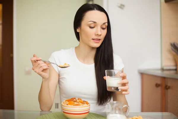 Brunetka jíst snídani s mlékem v kuchyni — Stock fotografie