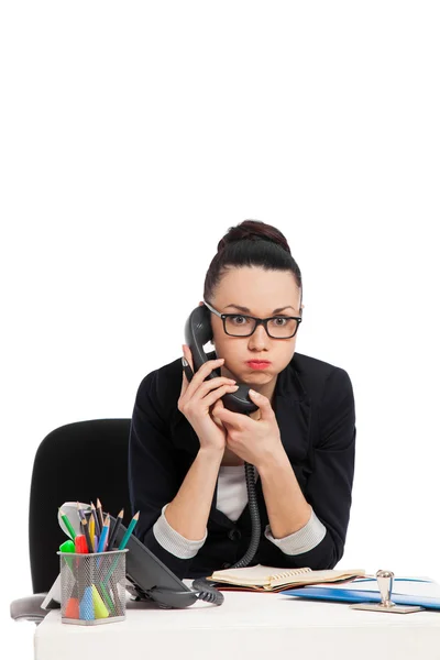 Secretário descontente falando ao telefone sentado sobre a mesa — Fotografia de Stock