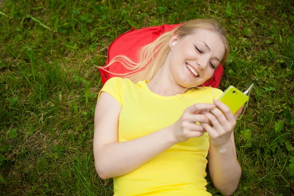 Kız holding cep telefonu ve beyaz kulaklık ile müzik dinleme — Stok fotoğraf