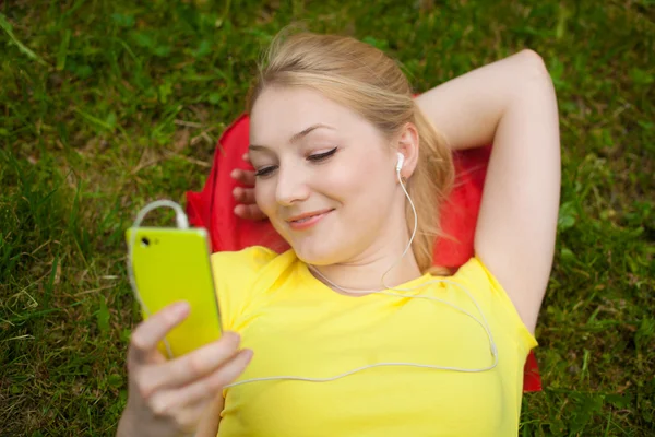 Ragazza che tiene il telefono cellulare e ascoltare musica con cuffie bianche — Foto Stock