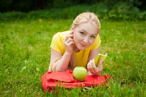 Ragazza che tiene il telefono cellulare e ascoltare musica con cuffie bianche — Foto Stock