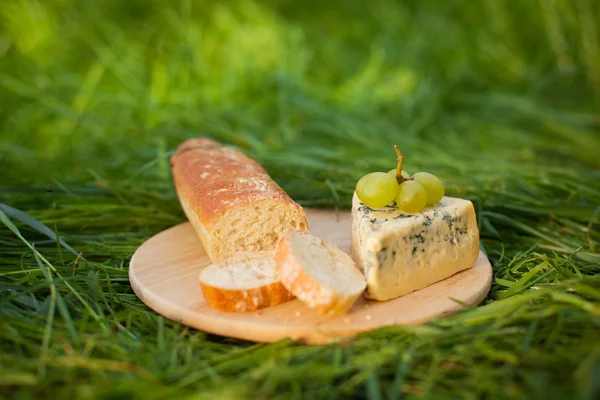 Μπλε τυρί με σταφύλια και μπαγκέτα στο ξύλινο πιάτο Εικόνα Αρχείου