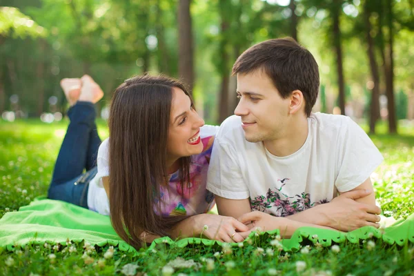 Sonriendo jóvenes amantes en el parque acostado Fotos de stock