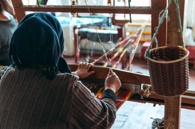 Geleneksel pedal dokuma tezgahında kumaş ören kadın